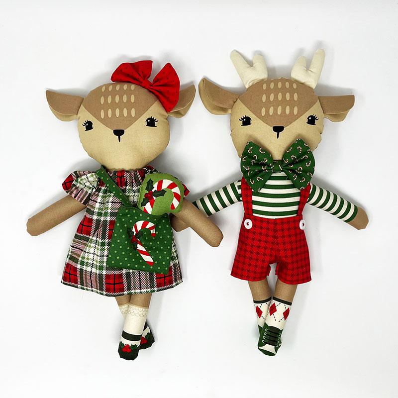 Two stuffed deer toys, one in a dress and the other in overalls, on a white background.